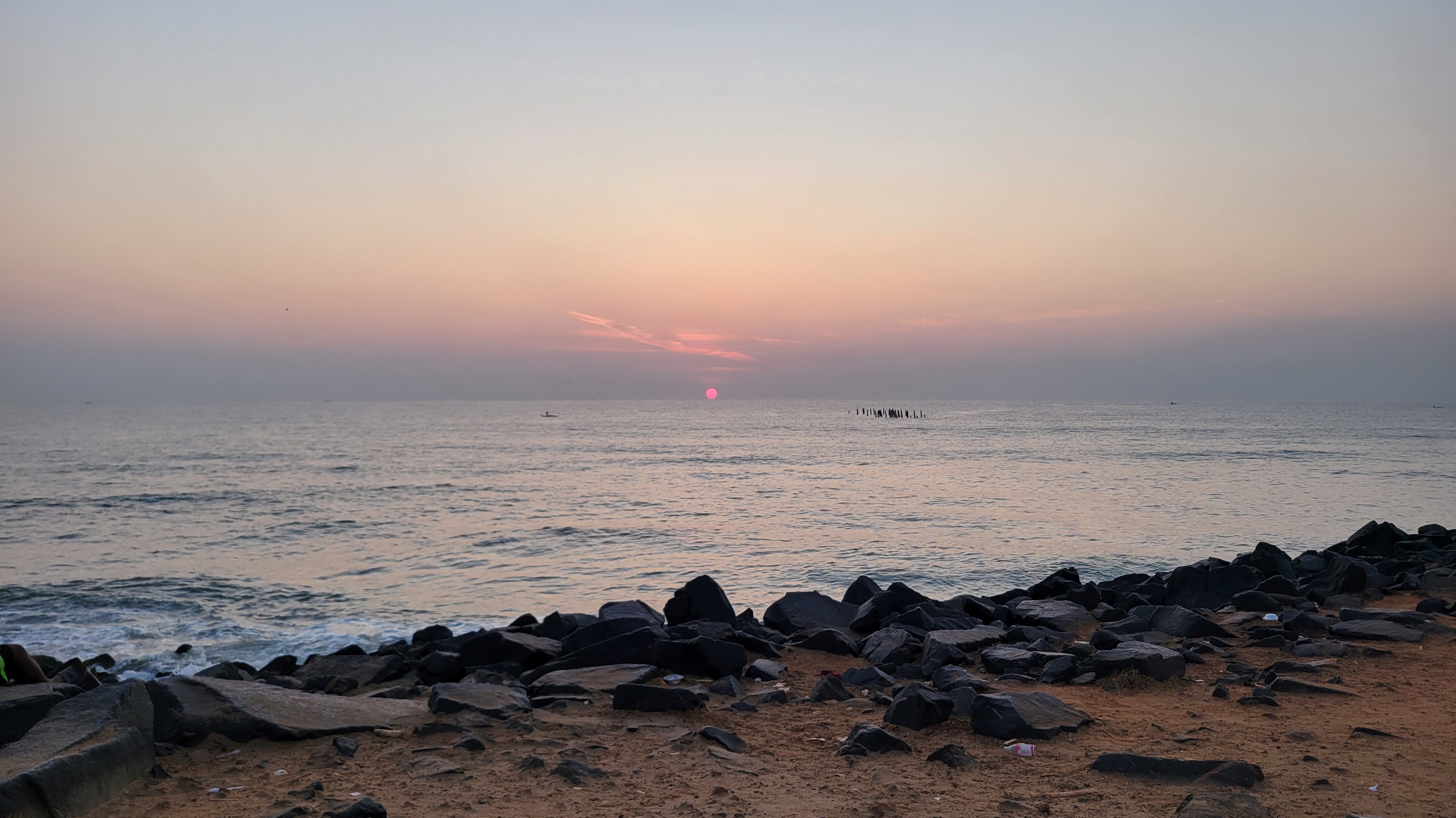 The orange orb of the sun peeking up as it rises from the waters near Pondicherry.